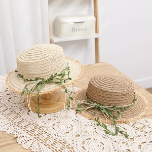 Dettaglio di cappelli da sole in rafia con decoro a foglia e tesa con frange naturali