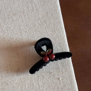Detail of vintage black velvet cherry hair claw clip on a rustic linen and wood surface