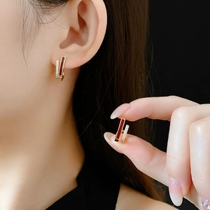 Vue détaillée d'une boucle d'oreille dorée avec émail rouge et pierres de zircon