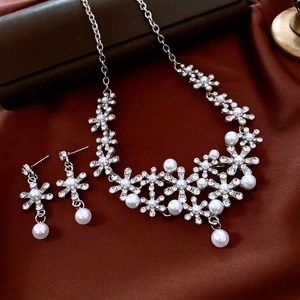 Detail of floral necklace and earrings with rhinestones and white pearls on brown satin