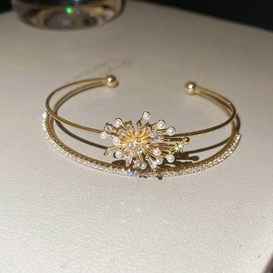 Detail of double-layer gold bangle with central starburst motif, pearls, and zircons