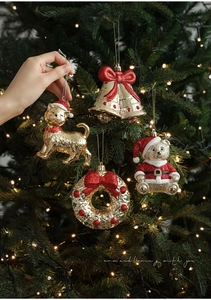 Close-up of golden and red Christmas cat ornament with glitter on a lit holiday tree