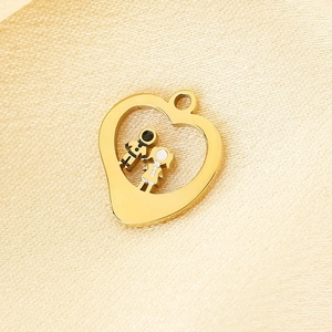 Detailed view of a gold heart pendant with enamel cartoon figures on gold textured fabric
