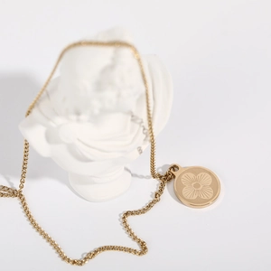 Detail of a vintage gold clover pendant on a curb chain displayed on a white bust