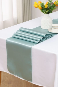 Detail of elegant teal satin table runner with smooth glossy texture on white cloth
