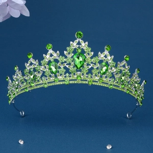 Macro detail of silver tiara featuring vibrant green rhinestones in Baroque style
