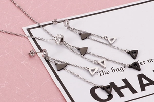 Detail of silver stainless steel jewelry set with geometric triangles and long tassels