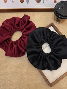 Detail of red and black jacquard satin scrunchies with elegant rose embroidery texture