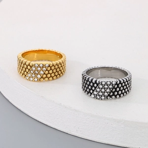 Close-up of wide stainless steel rings featuring retro beaded texture and diagonal cubic zirconia