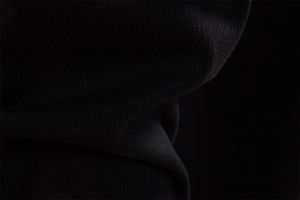Macro shot of black premium textured fabric showing weave detail and drape on casual pants