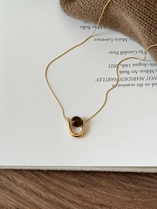 Macro detail of U-shaped gold necklace with brown tiger eye bead on vintage art book