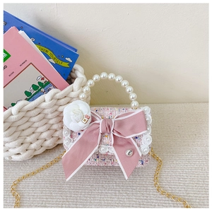 Detail of pink tweed girl's handbag with large bow, pearl trim and camellia flower