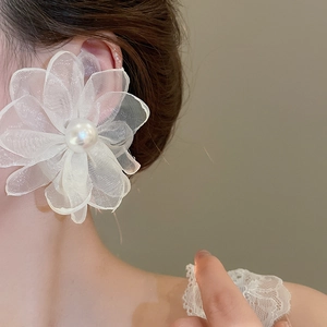 Close-up of white chiffon flower earrings with pearl center on a female model