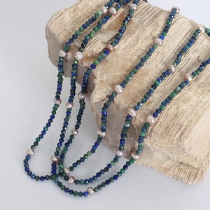 Lapis lazuli and freshwater pearl beaded necklace draped on a natural wood base