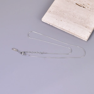 Detailed macro view of the silver snake chain necklace featuring K18 stamp on the tag