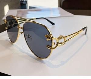 Detail shot of golden aviator frame featuring an intricate leopard head emblem on the hinge