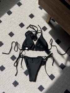 Flat lay of black halter bikini with a 3D satin rose detail and side-tie bottoms