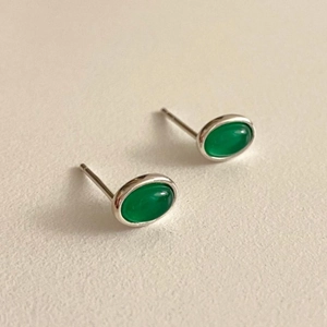 Macro shot of oval emerald green agate studs with polished silver-tone metal settings