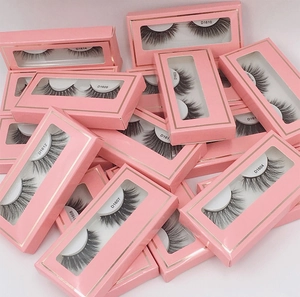 Macro view of multiple fake eyelashes in pink boxes with transparent windows showing detail