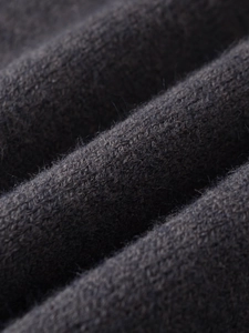 Macro detail of charcoal grey rib-knit fabric texture with soft natural wool fibers