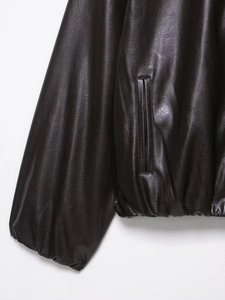 Detail shot of deep brown vintage faux leather jacket showing stitching and grain texture