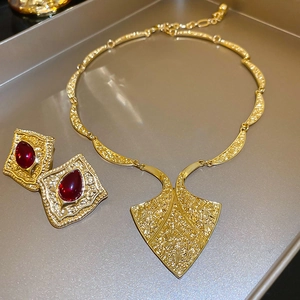 Detailed view of vintage gold jewelry set with embossed texture and red gemstones
