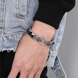 Detalle de una pulsera punk para hombre con cabeza de dragón en cuero negro trenzado