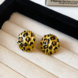 Macro shot of gold leopard print hoop earrings resting in a beige velvet jewelry organizer