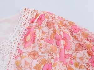 Dettaglio di tessuto in chiffon floreale rosa con pizzo bianco e cucitura a pieghe