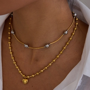 Gros plan d'un collier ras du cou et d'un pendentif cœur doré portés par un mannequin