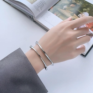 Brazaletes minimalistas Mobius de plata usados como pulseras a capas en la muñeca