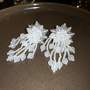 Detail of floral beaded tassel earrings with matte white beads and faux pearls on a tray