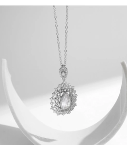 Macro view of a teardrop crystal pendant in an ornate silver setting on an O-chain