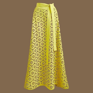 Detail of bright yellow maxi skirt featuring intricate hollow flower cutouts and waist tie