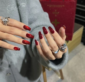 Detail of red cat eye press-on nails in long coffin shape with glossy shimmer finish