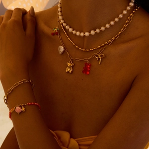 Layered gold chain and pearl necklace set with cherry, bear and heart pendants