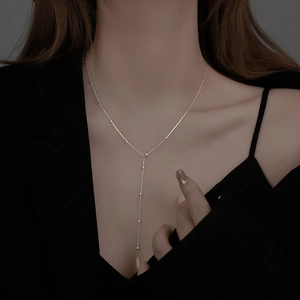 Minimalist silver Y-shaped tassel necklace with round beads on a stylish model