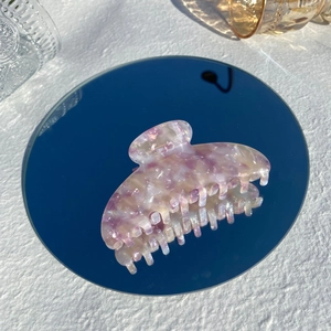 Macro detail of purple marble acetate hair claw clip reflecting on a round mirror