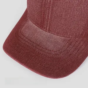 Detail of wide curved brim on vintage washed red baseball cap with fine stitching