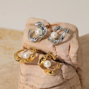 Irregular twisted C-shape pearl stud earrings in gold and silver finish on stones