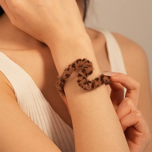 Detail of leopard print plush hair tie on wrist featuring soft faux fur and elastic band