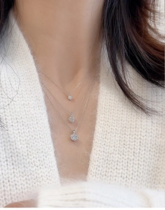 Three classic silver moissanite necklaces layered on model showing elegant round pendants