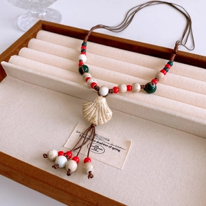 Detail of bohemian shell pendant with colorful beads and handmade woven cord tassel