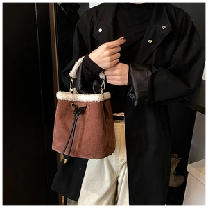 Close-up of brown suede bucket bag with white faux fur trim and black drawstring detail