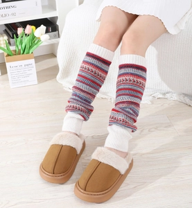 Détail de jambières en maille bohème rayée avec des mules en fausse fourrure pelucheuse à la maison