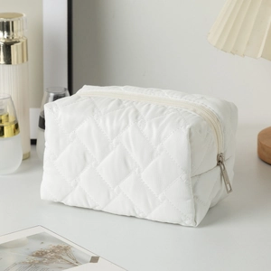 Detail of white quilted cosmetic bag with large diamond pattern and smooth zipper closure