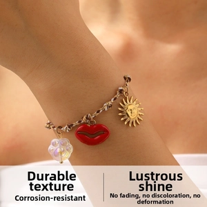 Detail of woven rope bracelet featuring golden sun, red lips and rainbow cat paw charms