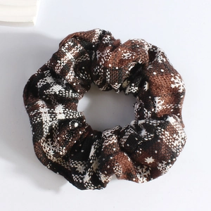 Detail of plush brown scrunchie with white snowflake patterns and knitted texture