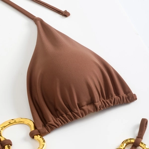 Close-up of brown bikini top featuring ribbed fabric and decorative gold metal rings