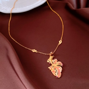 Detail of 24K gold plated fish pendant with pink enamel and crystals on silk fabric